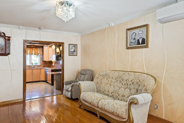 living area featuring wood-type flooring, sink, a wall mounted AC, a chandelier, and crown molding