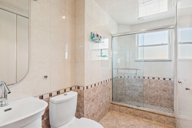 bathroom with tile walls, sink, toilet, and an enclosed shower