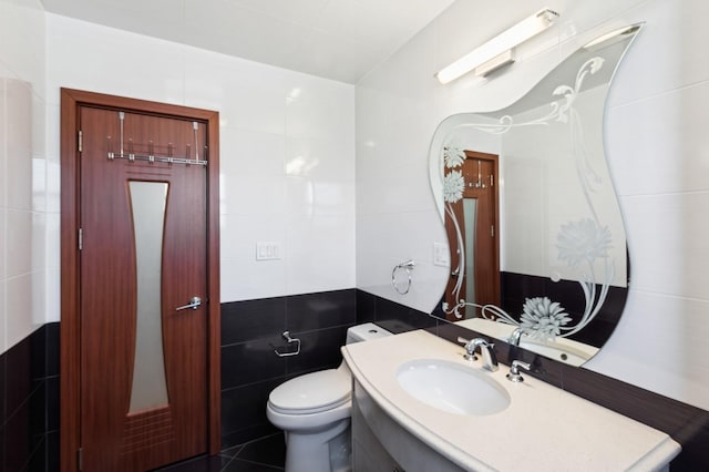 bathroom featuring vanity, tile walls, and toilet