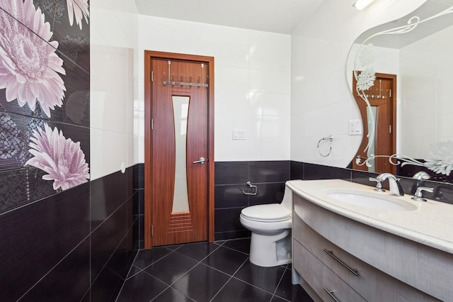 bathroom featuring vanity, toilet, tile patterned flooring, and tile walls