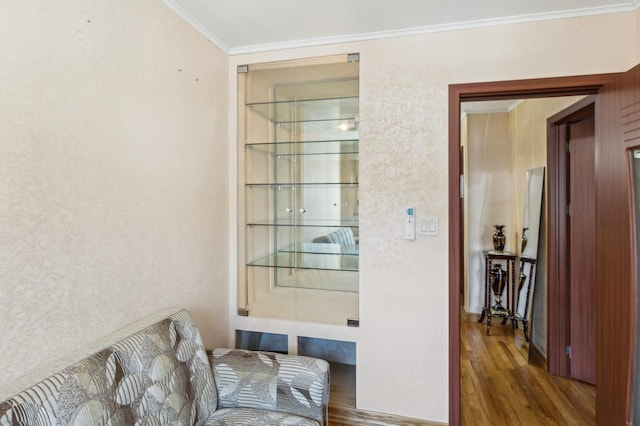 living area featuring hardwood / wood-style flooring, ornamental molding, and built in features