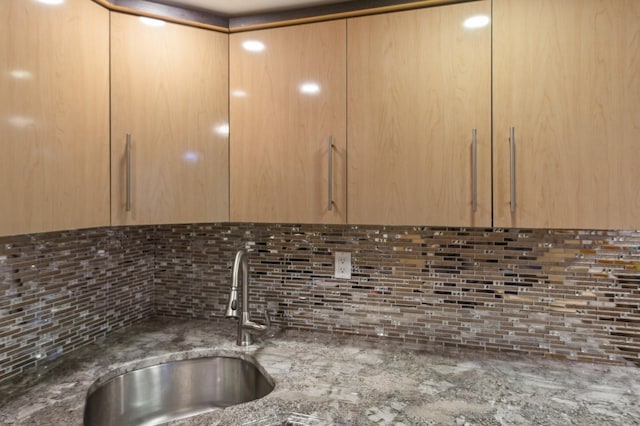 room details featuring light brown cabinetry, backsplash, sink, and dark stone counters