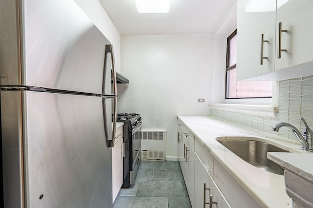 kitchen with sink, white cabinets, stainless steel fridge, and gas stove