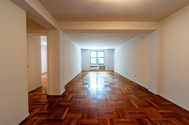 spare room featuring radiator heating unit and dark parquet floors