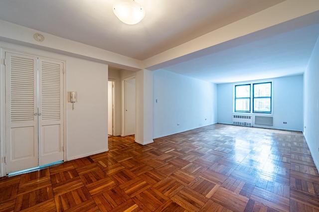 spare room with radiator heating unit and dark parquet flooring