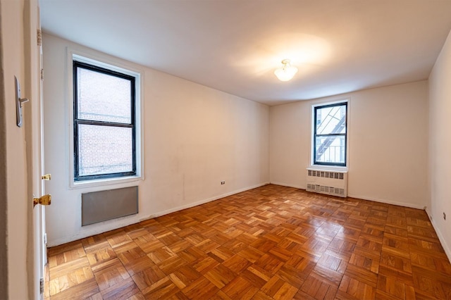 unfurnished room featuring light parquet floors and radiator heating unit