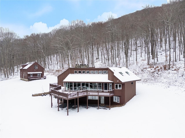 snow covered back of property with a deck