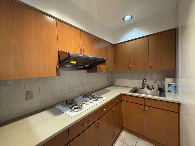 kitchen with light tile patterned floors, white gas stovetop, tasteful backsplash, and sink