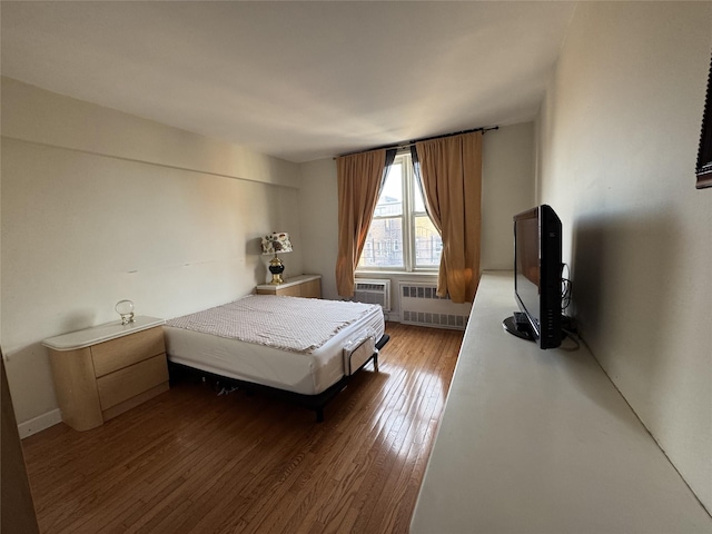 bedroom with radiator and hardwood / wood-style floors