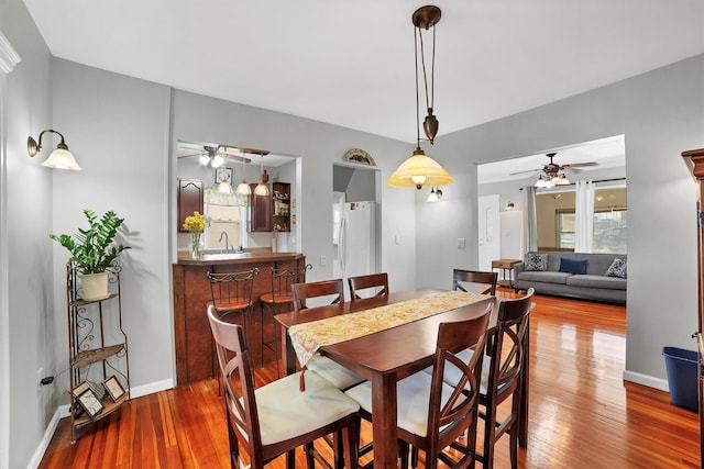 dining area featuring ceiling fan, wood-type flooring, and wet bar