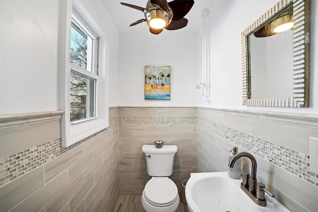 bathroom featuring sink, a wealth of natural light, toilet, and tile walls