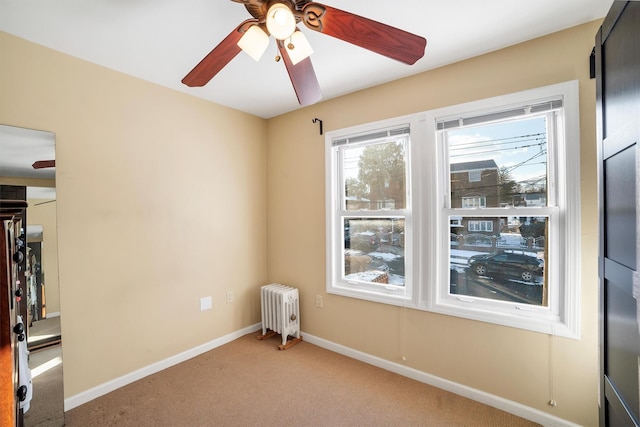 unfurnished room featuring carpet floors, radiator, and ceiling fan