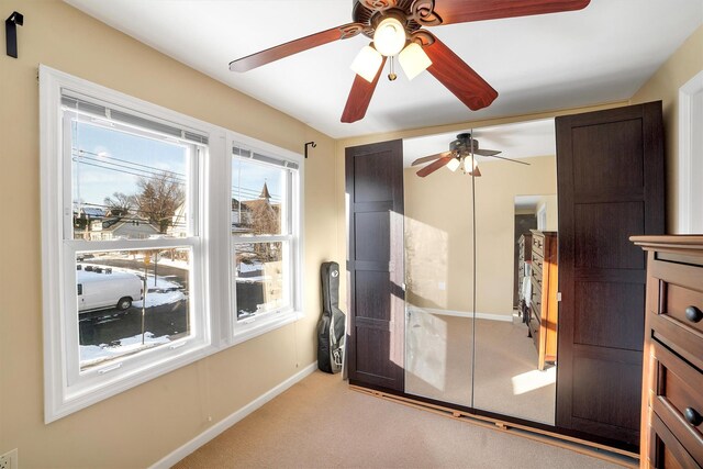 bedroom featuring multiple windows, light colored carpet, a closet, and ceiling fan