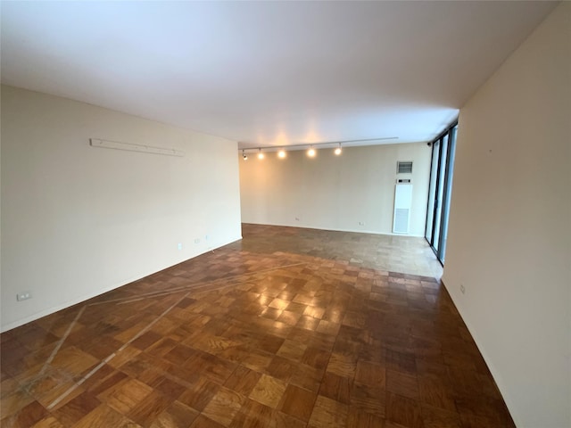 unfurnished room featuring rail lighting and dark parquet flooring