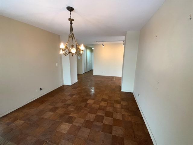 unfurnished dining area featuring rail lighting, dark parquet floors, and a chandelier