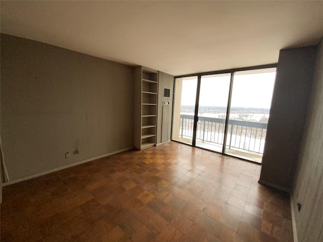 unfurnished room with a water view and a wall of windows