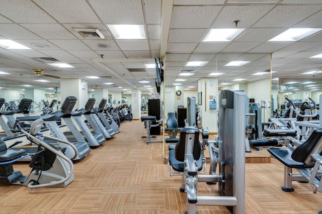 exercise room featuring a paneled ceiling and light carpet