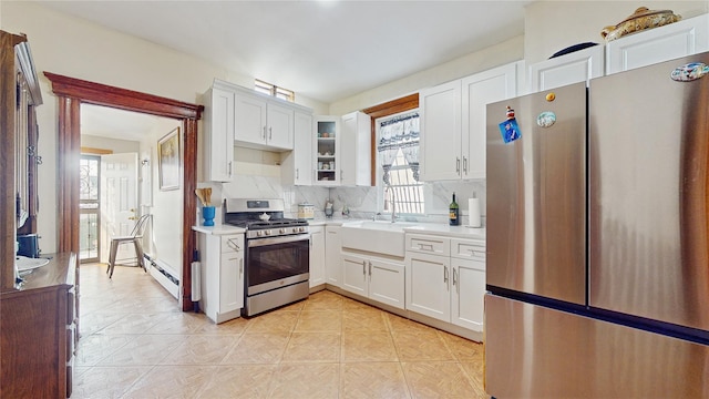 kitchen featuring baseboard heating, stainless steel appliances, white cabinets, and sink