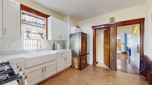 kitchen with tasteful backsplash, appliances with stainless steel finishes, sink, and white cabinetry