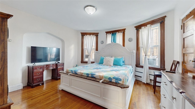 bedroom featuring light hardwood / wood-style floors, cooling unit, and a baseboard heating unit