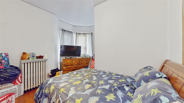 bedroom with radiator heating unit and hardwood / wood-style flooring