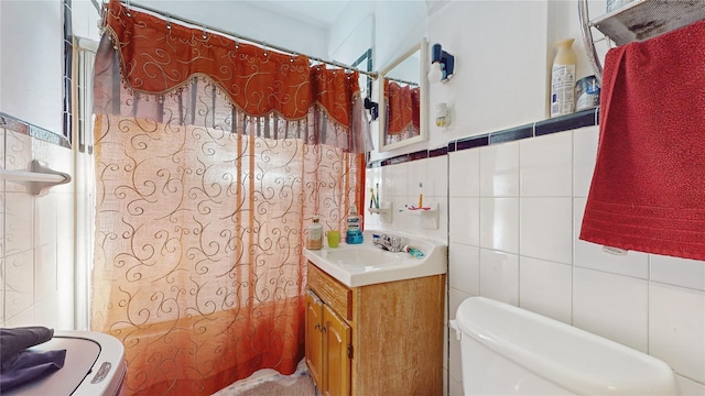 bathroom with toilet, tile walls, and vanity