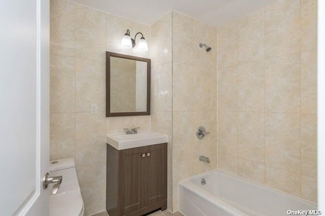 full bathroom with tile walls, tiled shower / bath combo, vanity, and toilet