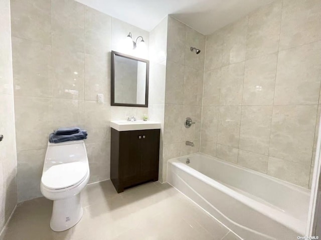 full bathroom featuring toilet, tiled shower / bath combo, tile patterned flooring, tile walls, and vanity