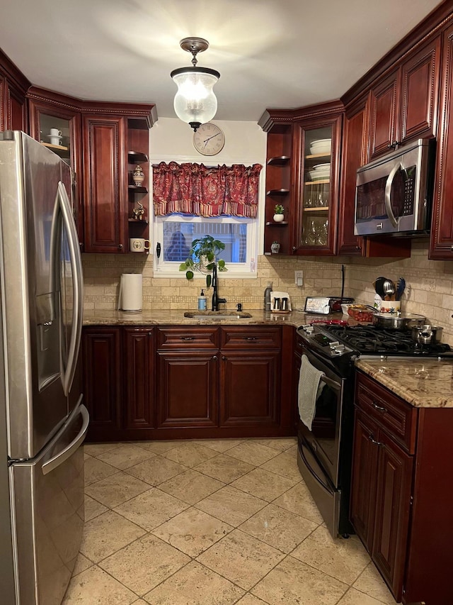 kitchen with appliances with stainless steel finishes, light tile patterned floors, decorative backsplash, sink, and light stone counters