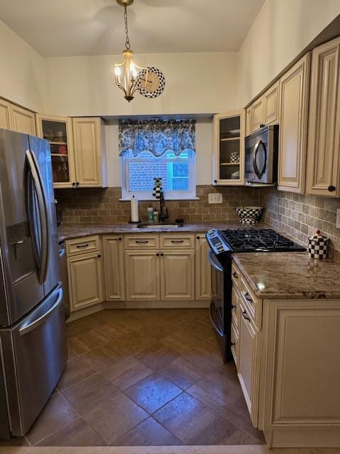 kitchen with a notable chandelier, tasteful backsplash, range with gas cooktop, pendant lighting, and stainless steel fridge