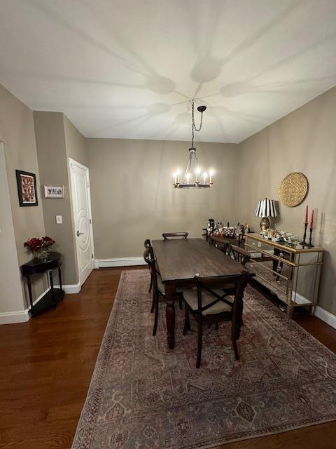 dining room with a baseboard heating unit, dark hardwood / wood-style floors, and an inviting chandelier