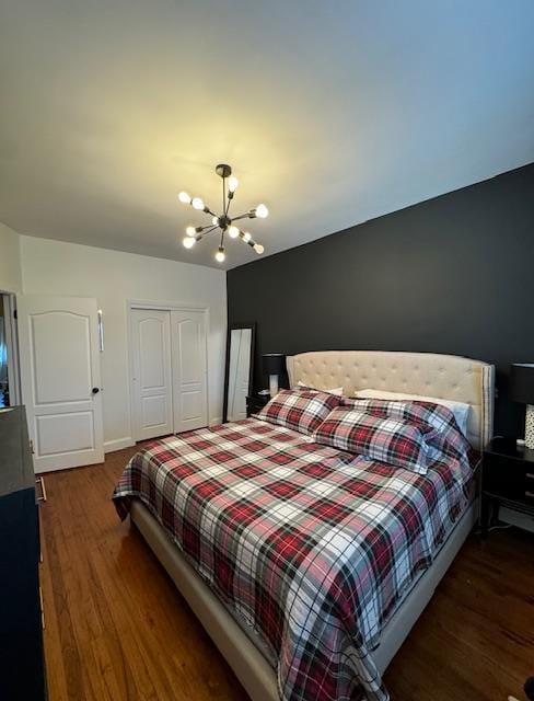 bedroom with a closet, an inviting chandelier, and dark hardwood / wood-style floors