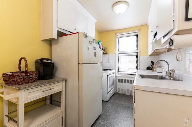 kitchen featuring white appliances, white cabinets, radiator, sink, and backsplash