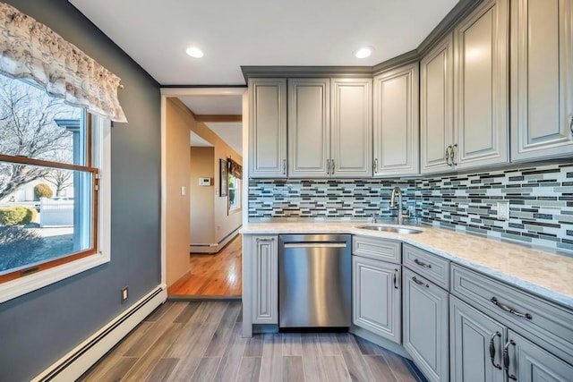 kitchen with a baseboard radiator, dishwasher, sink, gray cabinets, and light stone counters