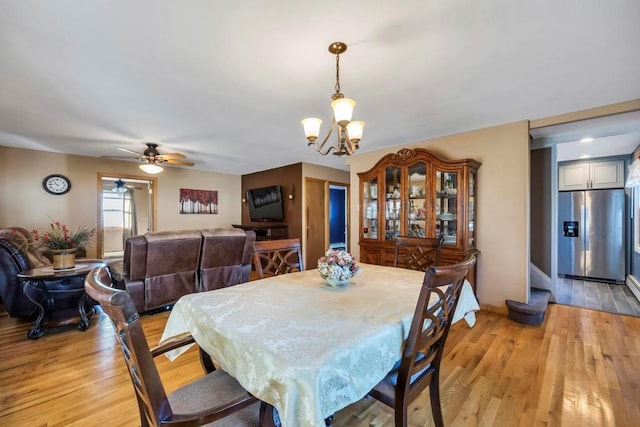 dining room featuring light wood-type flooring and ceiling fan with notable chandelier