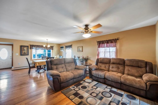 living room with wood-type flooring, baseboard heating, and ceiling fan with notable chandelier