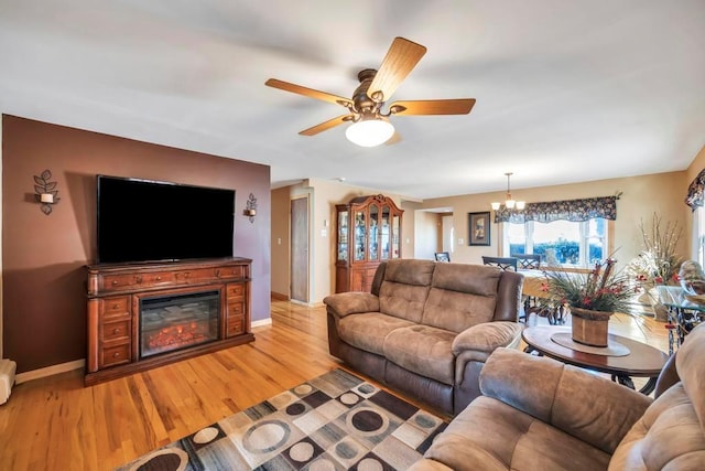 living room with light wood-type flooring and ceiling fan with notable chandelier