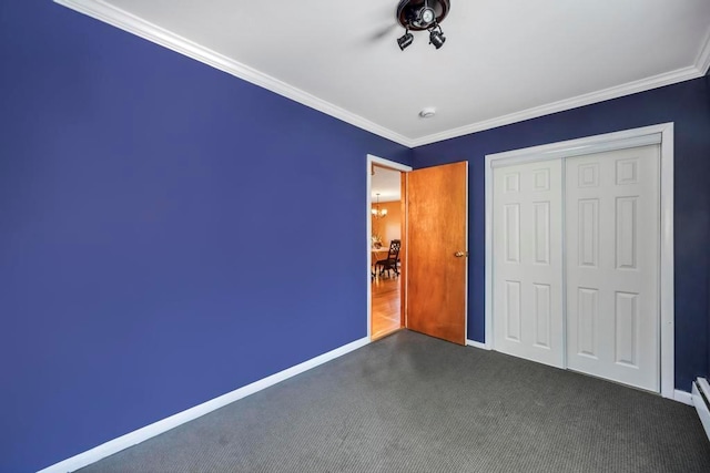 unfurnished bedroom with a baseboard heating unit, a closet, crown molding, and dark colored carpet