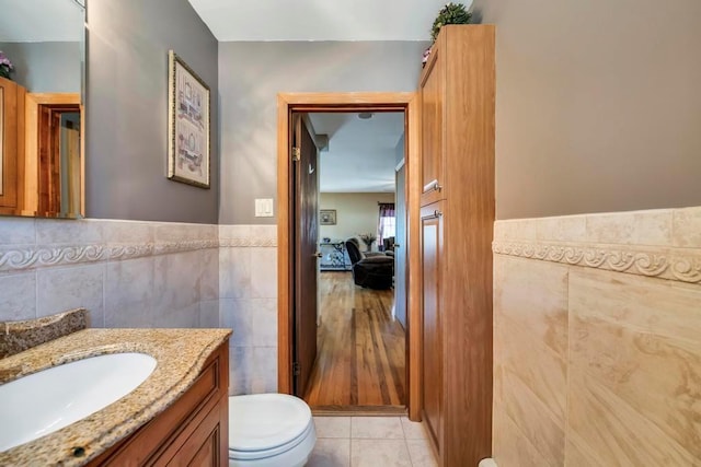 bathroom featuring toilet, tile patterned flooring, vanity, and tile walls