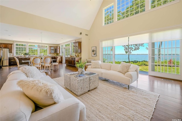 living room with a high ceiling, wood-type flooring, and a water view