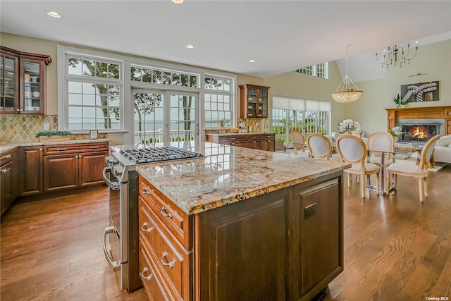 kitchen featuring a center island, decorative backsplash, french doors, gas stove, and light stone counters