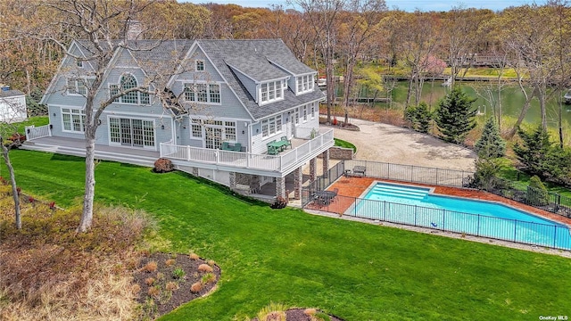 rear view of property featuring a balcony, a lawn, a swimming pool side deck with water view, and a patio