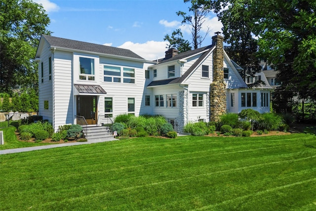 back of property featuring a chimney and a lawn