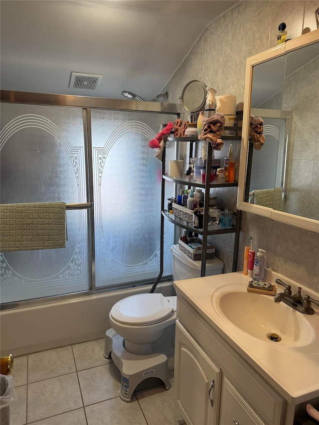 full bathroom featuring shower / bath combination with glass door, lofted ceiling, tile patterned floors, vanity, and tile walls