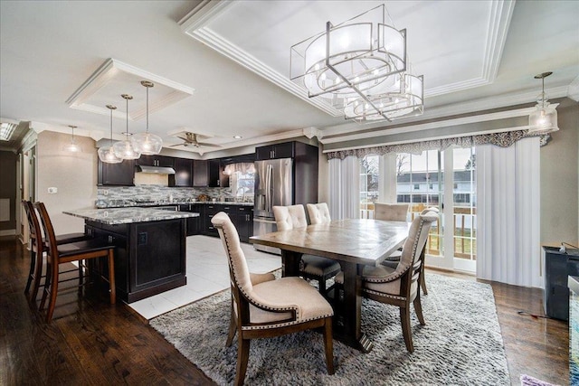 dining area featuring a raised ceiling, crown molding, hardwood / wood-style floors, and an inviting chandelier