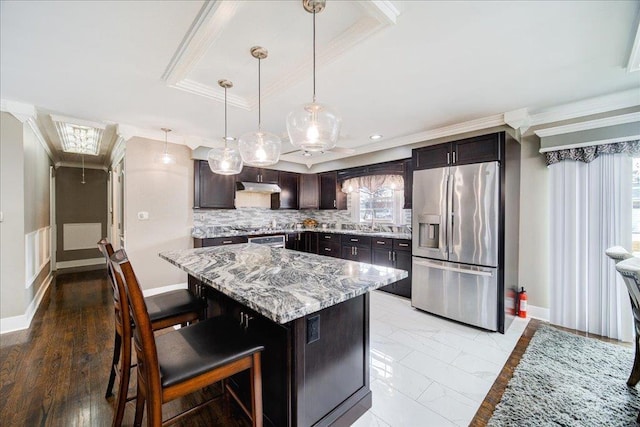 kitchen with pendant lighting, a breakfast bar area, appliances with stainless steel finishes, tasteful backsplash, and a kitchen island