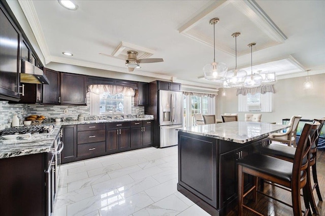 kitchen with hanging light fixtures, backsplash, stainless steel fridge, and a center island