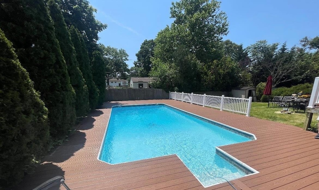 view of pool featuring a wooden deck and a storage unit