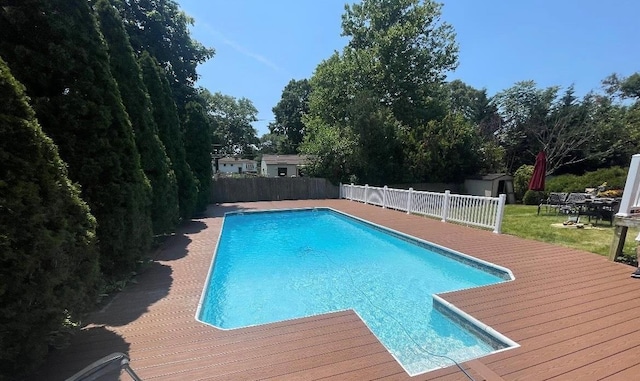 view of swimming pool featuring a shed and a wooden deck