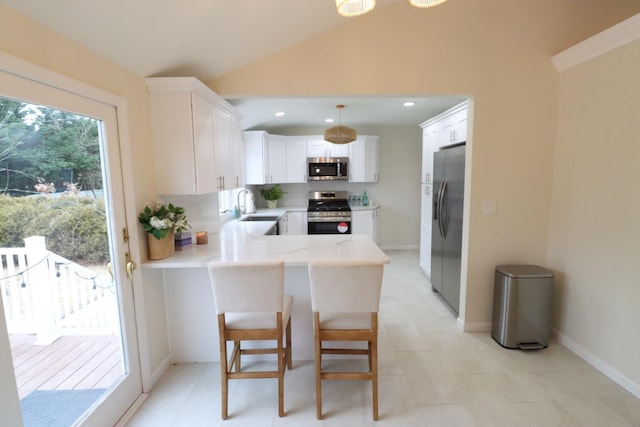 kitchen featuring lofted ceiling, sink, appliances with stainless steel finishes, white cabinets, and kitchen peninsula